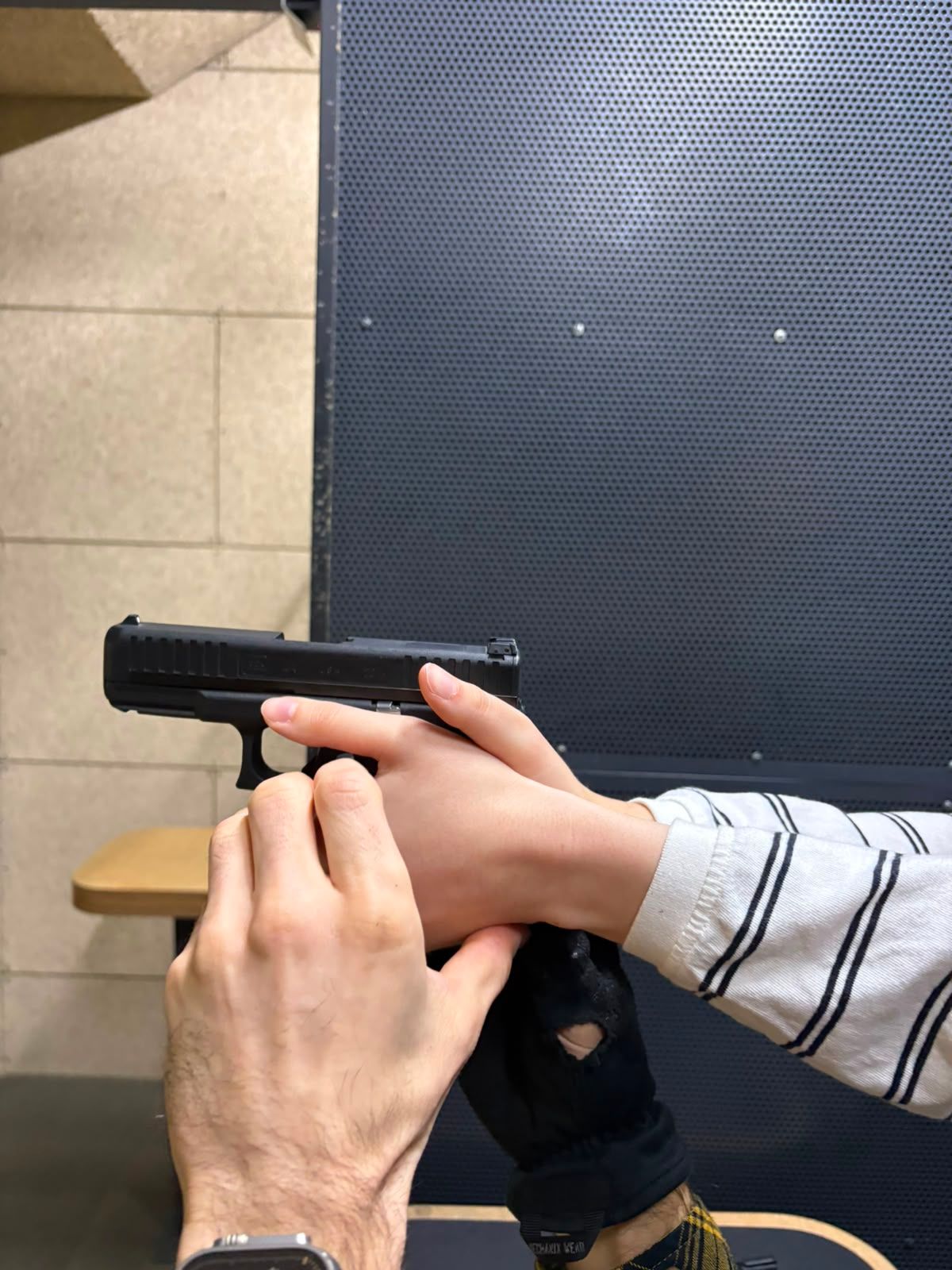 An instructor shows a first-time shooter the correct pistol grip, with the index finger resting along the frame